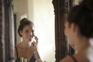Woman checking her skin in the mirror during a daily skincare routine